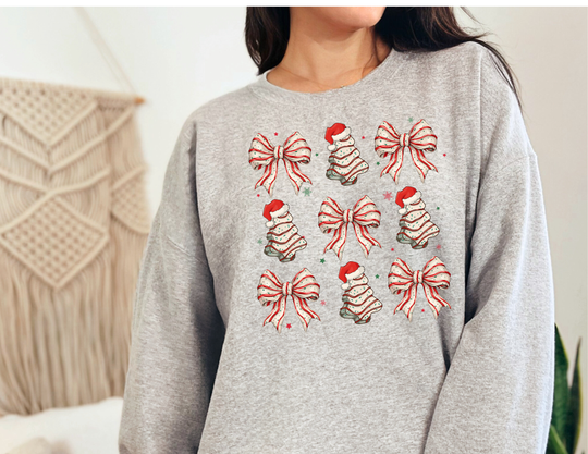 Cookies and Bows Crew sweatshirt with Christmas icons grid, worn by a person, featuring bows and trees with Santa hats, offering comfort and festive style.