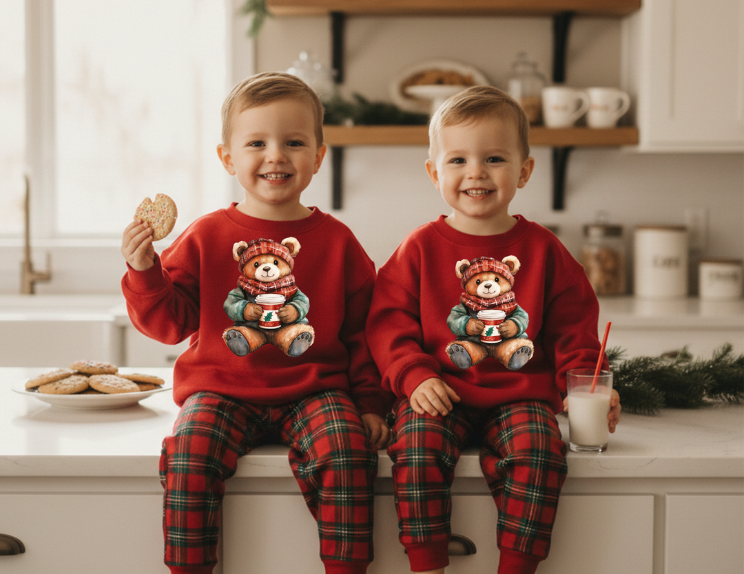 Young twins wearing Old Money Bear Toddler Crews with holiday-themed bear designs, sitting on a kitchen counter with cookies and milk, embodying cozy festive charm.