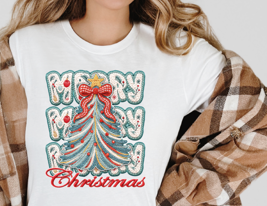 Person wearing Merry Christmas Tree Tee with festive embroidered-style graphic, featuring a yarn-like Christmas tree and MERRY MERRY Christmas text, under a plaid shacket.