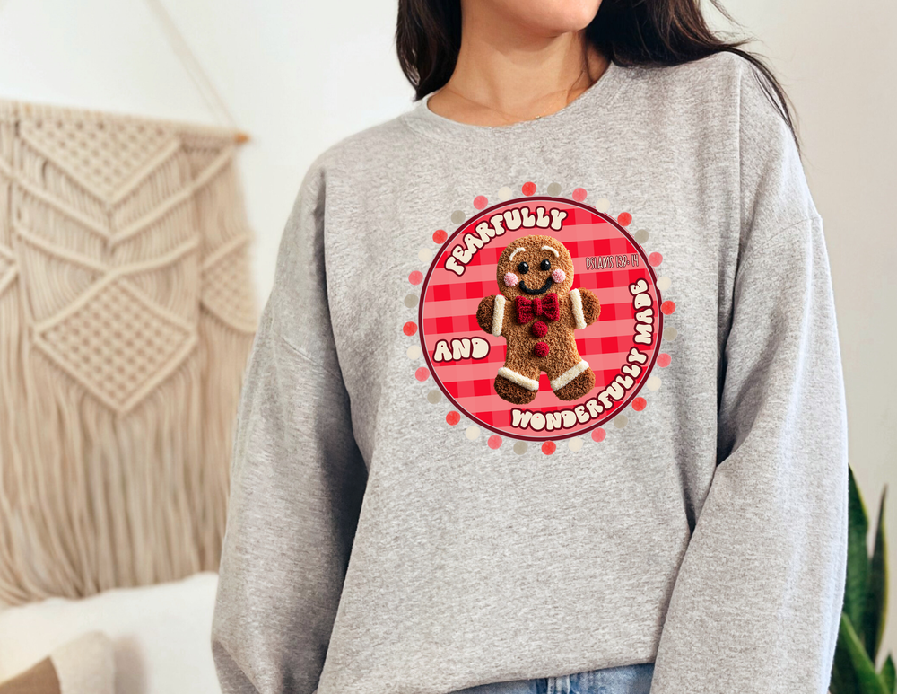 Person wearing the Wonderfully Made Crew sweatshirt with gingerbread-man graphic and scripture, showcasing comfort and style with ribbed-knit collar and durable stitching.