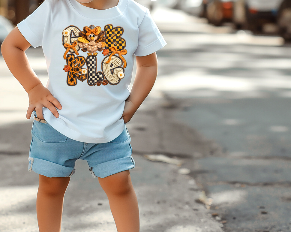 Child wearing Gobble Kids Tee with autumn-themed appliqués and denim shorts, showcasing Faith Family Designs' playful and comfortable graphic t-shirt for active kids.