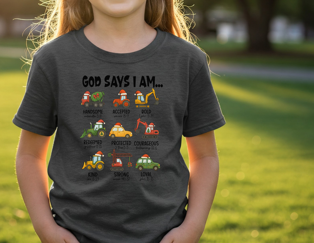 Child wearing God Says Christmas Truck Toddler Tee with cartoon vehicles and Bible references, standing on a lawn, embodying traits like courageous and strong. Ideal for sensitive skin.