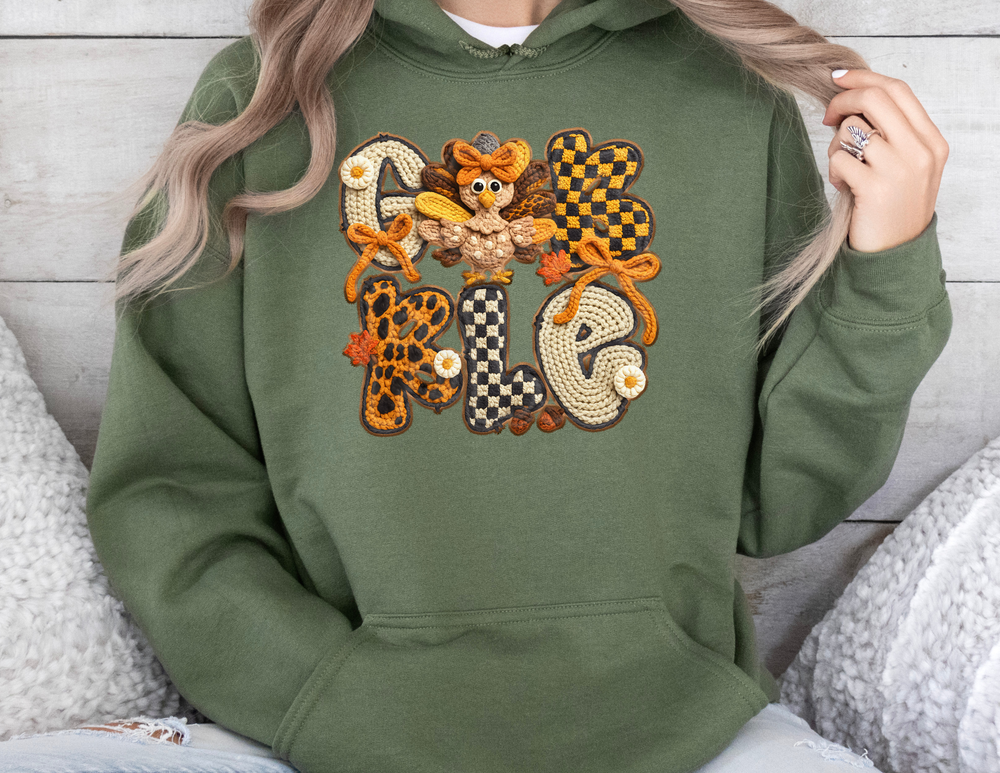 Gobble Hoodie with crochet-style GOBBLE applique, featuring patterns, bows, daisies, leaves, and a cartoon turkey. Modeled by a person, showcasing hoodie fit.