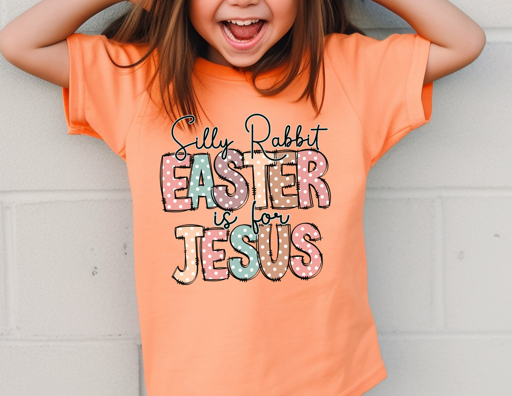 Girl smiling in an orange Silly Rabbit Easter is for Jesus Tee, perfect for toddlers with soft, durable cotton fabric, ideal for first adventures.