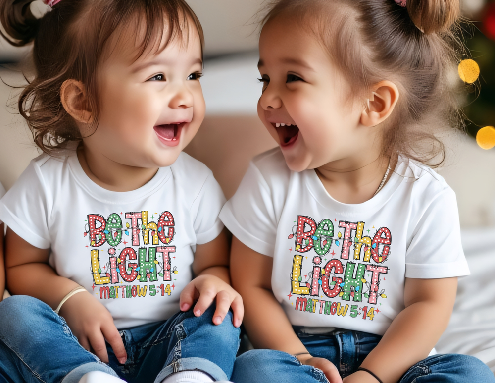 Toddlers in Be the Light tees share a joyful moment, showcasing Faith Family Designs' soft, durable, and stylish baby apparel.