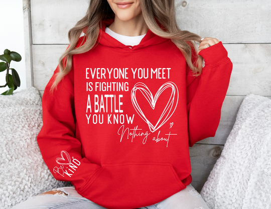 Person in cozy setting wearing Fighting a Battle Hoodie with heart and motivational message, emphasizing comfort and style from Faith Family Designs.