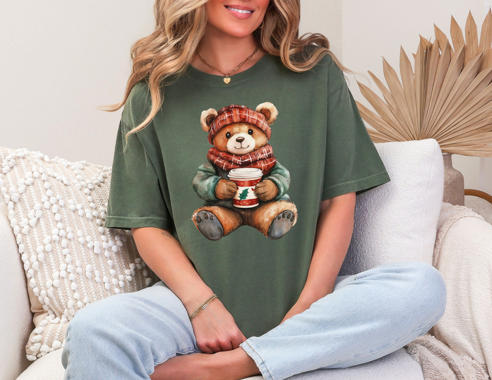 Person in light jeans wearing an Old Money Christmas Bear Tee with a teddy bear design, seated on a sofa, showcasing casual style and comfort.