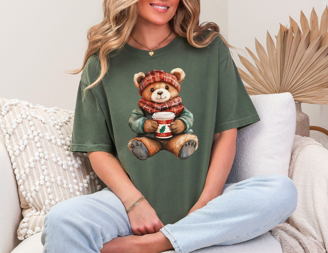 Person in light jeans wearing an Old Money Christmas Bear Tee with a teddy bear design, seated on a sofa, showcasing casual style and comfort.