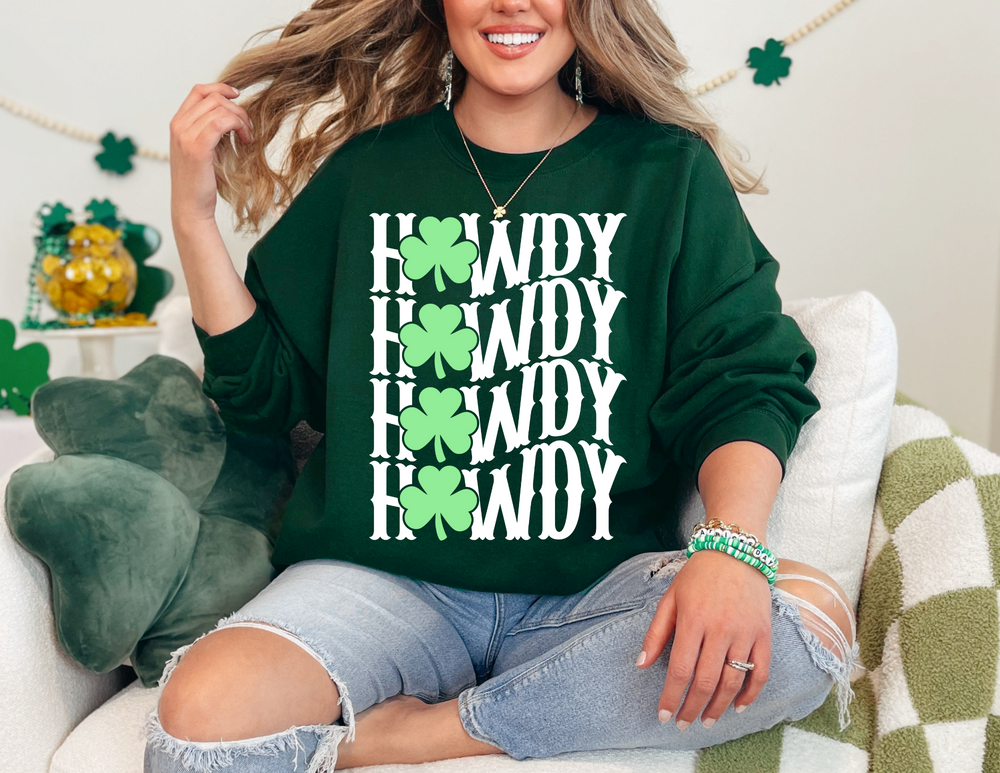 Woman on couch wearing Howdy Lucky Crew sweatshirt, showcasing its comfortable fit and ribbed collar. Ideal for casual settings, featuring a green clover design.