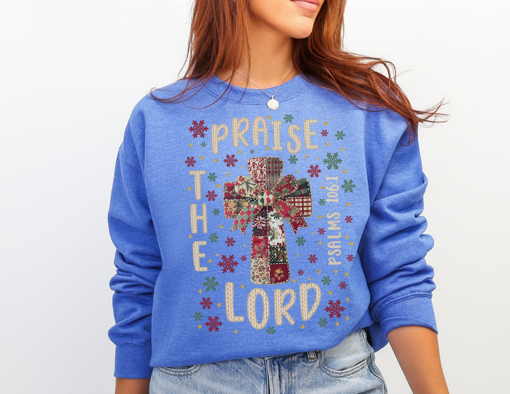 Person wearing a Praise the Lord Crew sweatshirt with a festive cross and Psalms 106:1, capturing a cozy, faith-inspired design by Faith Family Designs.