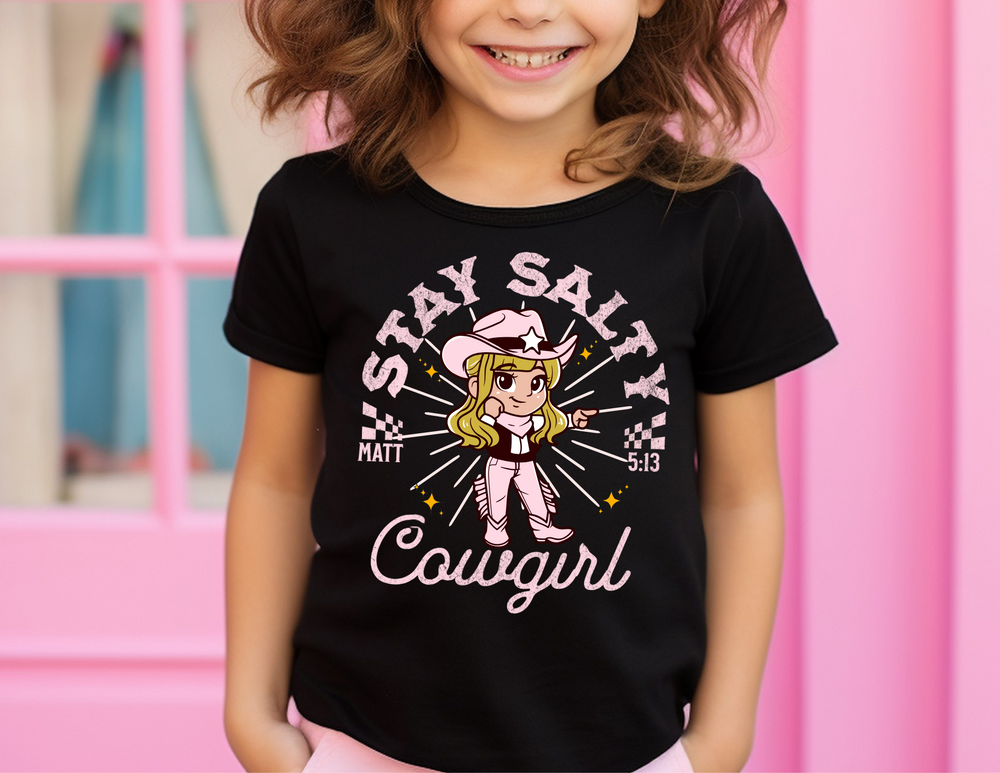 Salty Cowgirl Tee featuring a smiling girl cartoon, perfect for toddlers' sensitive skin with high-quality print. Classic fit, 100% cotton, ideal for early adventures.