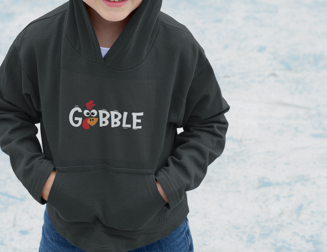 Youth Gobble Hoodie: A child in a soft, cotton-poly blend sweatshirt with kangaroo pocket. Reinforced neck, cozy fleece, and cartoon bird logo detail. Ideal for winter fun.