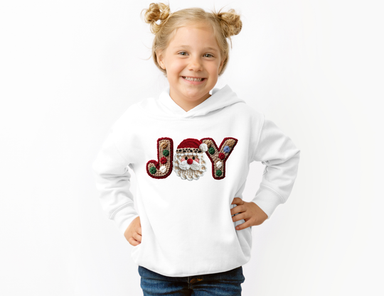 Young girl wearing the Joy Hoodie with festive embroidered design, smiling confidently with hands on hips, showcasing the durable, cozy toddler hoodie.