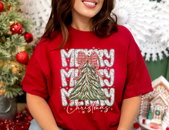 Merry Merry Merry Christmas Tee featuring festive tree graphic and Christmas script, worn by person, showcasing Faith Family Designs' trendy, high-quality cotton apparel.