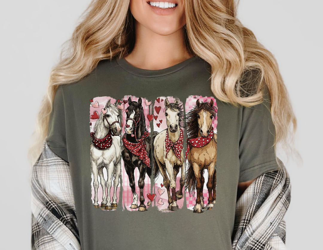 Woman wearing muted green Horse Valentine Tee with four hand-drawn horses in bandanas, surrounded by floating hearts. Comfortable, soft cotton tee with a retail fit.