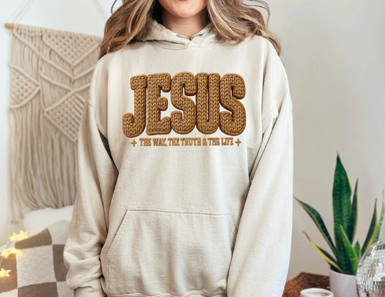 Person wearing a light-beige Jesus Hoodie with The Way, The Truth & The Life text, showcasing a cozy, faith-inspired design from Faith Family Designs.