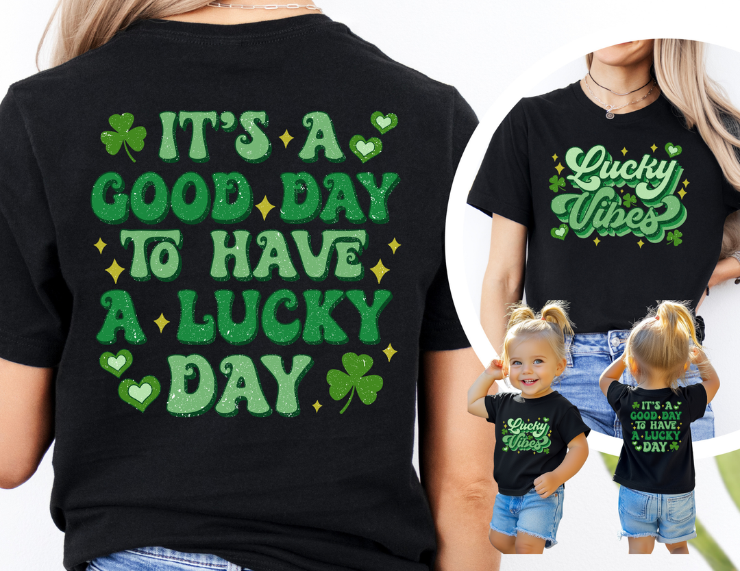 Good Day Lucky Day Tee features “Lucky Vibes” with shamrocks on front, “It’s a Good Day to Have a Lucky Day” slogan on back, shown on adult and child.