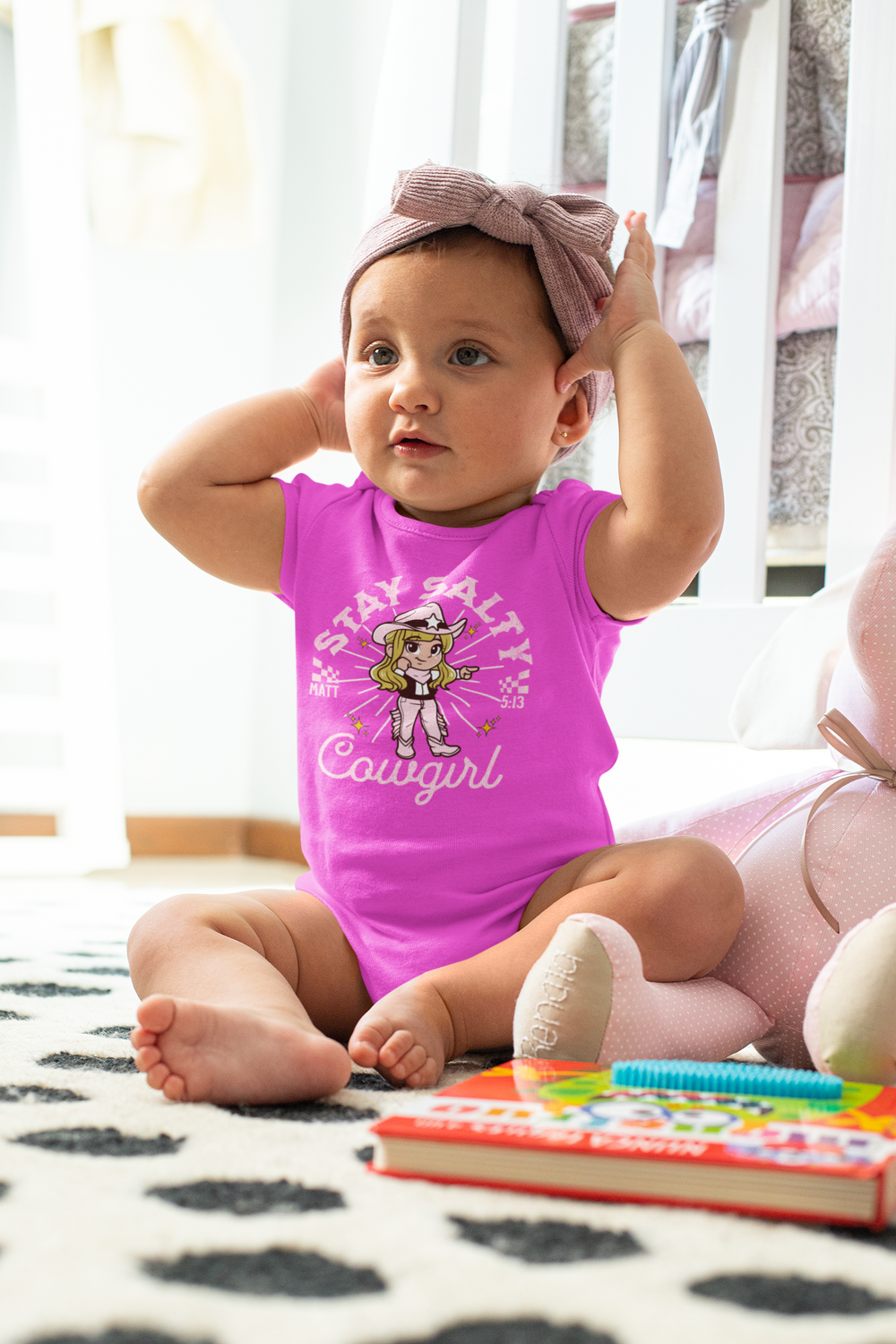 Baby wearing the Salty Cowgirl Onesie with a cartoon graphic, showcasing soft, ring-spun cotton fabric, ideal for comfort and ease.