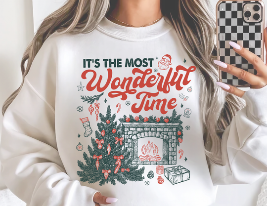 Person wearing Most Wonderful Time of the Year Crew sweatshirt with festive Christmas scene, capturing a mirror selfie. Cozy, oversized fit ideal for colder months.