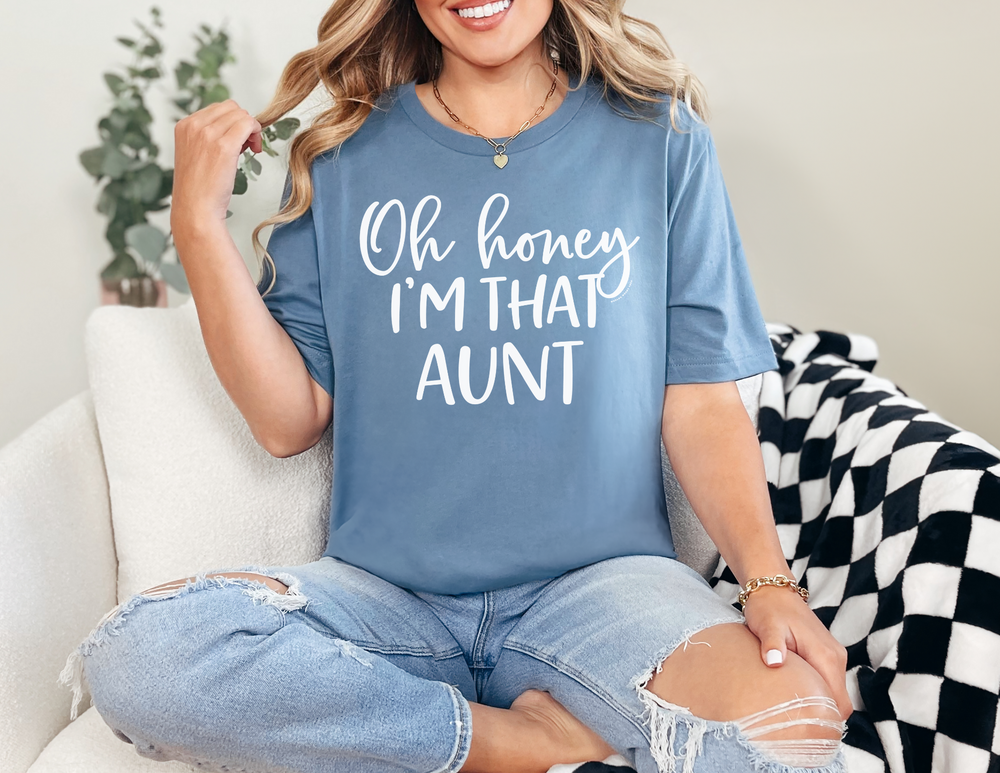 Woman wearing Oh Honey I'm that Aunt Tee, sitting on a couch, showcasing the relaxed fit and durable stitching of the 100% ring-spun cotton t-shirt.