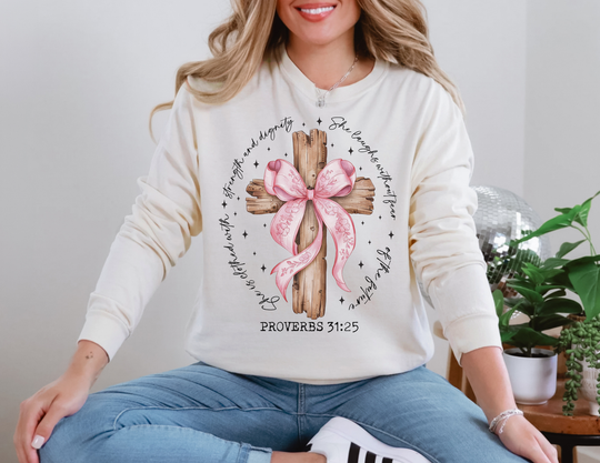 Person wearing the Proverbs 31:25 Long Sleeve Tee with a rustic cross and scripture graphic, seated cross-legged, showcasing the shirt's relaxed fit and soft fabric.