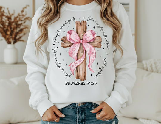 Person wearing a Proverbs 31:25 Crew sweatshirt featuring a rustic wooden cross with pink ribbon and hand-lettered verse, paired with blue jeans.