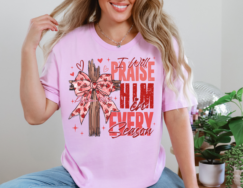 Praise in Every Season Heart Tee with wooden cross and bow graphic, surrounded by hearts and sparkles, showcasing Psalm 146:2. Classic unisex fit, soft cotton.