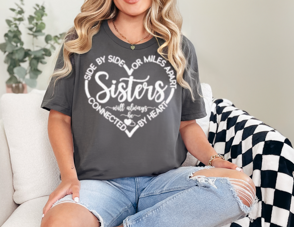 Woman wearing the Sisters At Heart Tee on a couch, showcasing the relaxed fit and durable stitching of this garment-dyed, ring-spun cotton t-shirt.