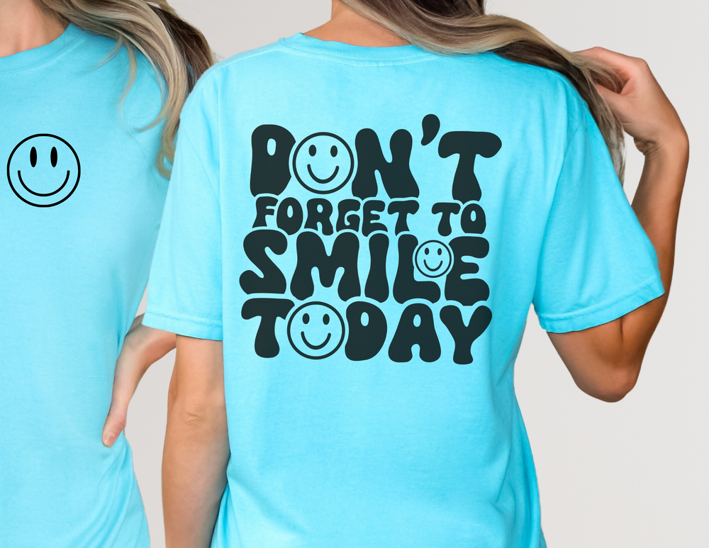 Don't Forget To Smile Today Tee featuring a blue smiley face design, worn by a person. Made from 100% ring-spun cotton for a soft, relaxed fit.