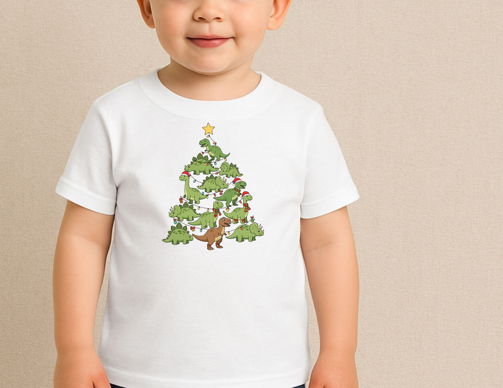 Toddler wearing Dino Tree Toddler Tee with whimsical dinosaur Christmas tree design, featuring Santa hats and holiday lights, perfect for sensitive skin and first adventures.