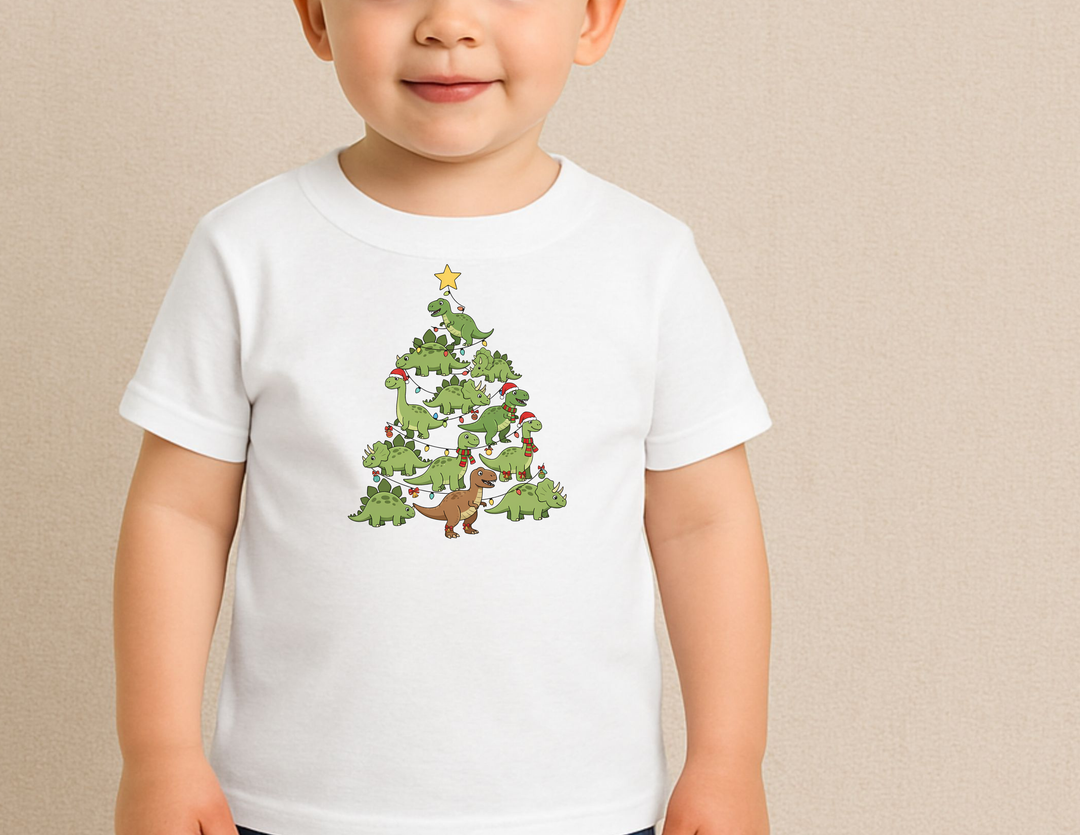 Toddler wearing Dino Tree Toddler Tee with whimsical dinosaur Christmas tree design, featuring Santa hats and holiday lights, perfect for sensitive skin and first adventures.