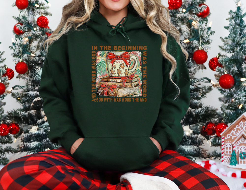 Cozy Christmas scene featuring In the Beginning Hoodie with a festive mug and biblical verse, surrounded by holiday decorations, perfect for warmth and style.