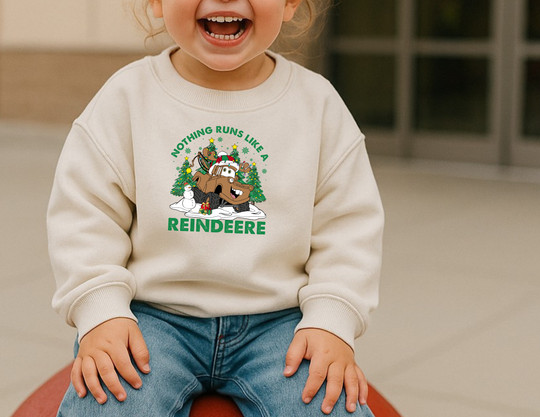 Toddler in a cream Reindeere Toddler Crew sweatshirt featuring a cartoon reindeer with tires, festive accessories, and the slogan Nothing runs like a Reindeer.