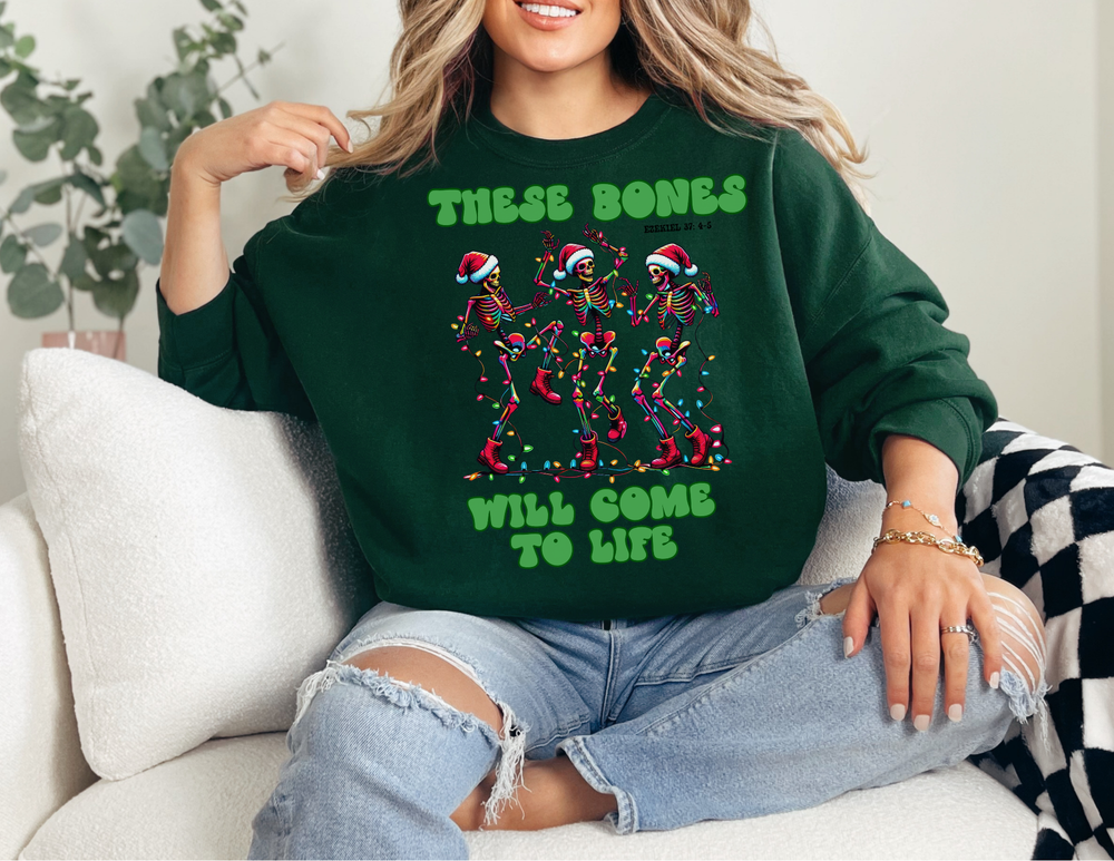 Woman on couch wearing Bones Come to Life Crew sweatshirt featuring festive skeletons in Santa hats, paired with ripped jeans and simple jewelry.