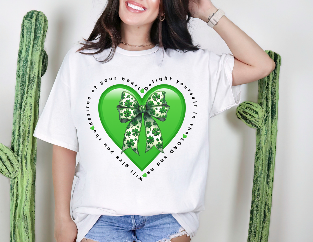 Delight in the LORD Tee: A white T-shirt with a glossy green heart and motivational text, featuring a clover-patterned bow, worn with denim shorts.