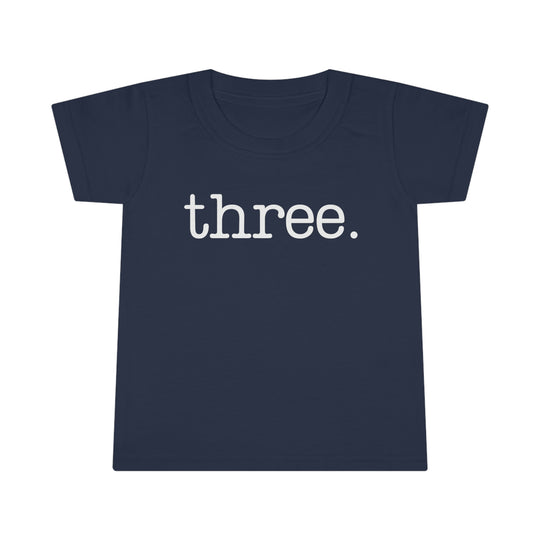 Three Toddler Tee, blue shirt with white text, close-up logo detail, 100% Ringspun cotton, classic fit, durable double-needle collar, sleeve, and bottom hems. Comfy and stylish for kids.