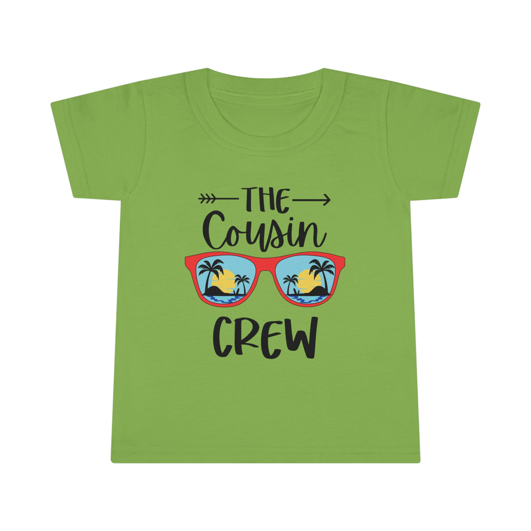 A personalized Cousin Crew Toddler Tee with a beach and palm tree graphic on a green shirt. Classic fit, high stitch density, and durable construction for comfort and style. Ideal for kids.