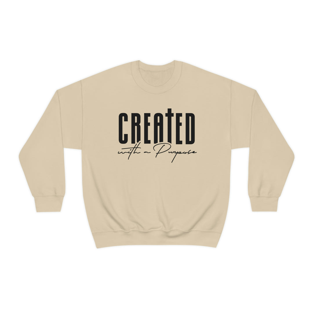 A beige crewneck sweatshirt with black text, ideal for any situation. Made from a blend of polyester and cotton, featuring a ribbed knit collar and a loose fit. Created With A Purpose Crewneck.