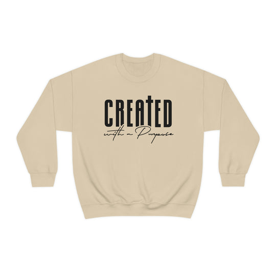 A beige crewneck sweatshirt with black text, ideal for any situation. Made from a blend of polyester and cotton, featuring a ribbed knit collar and a loose fit. Created With A Purpose Crewneck.