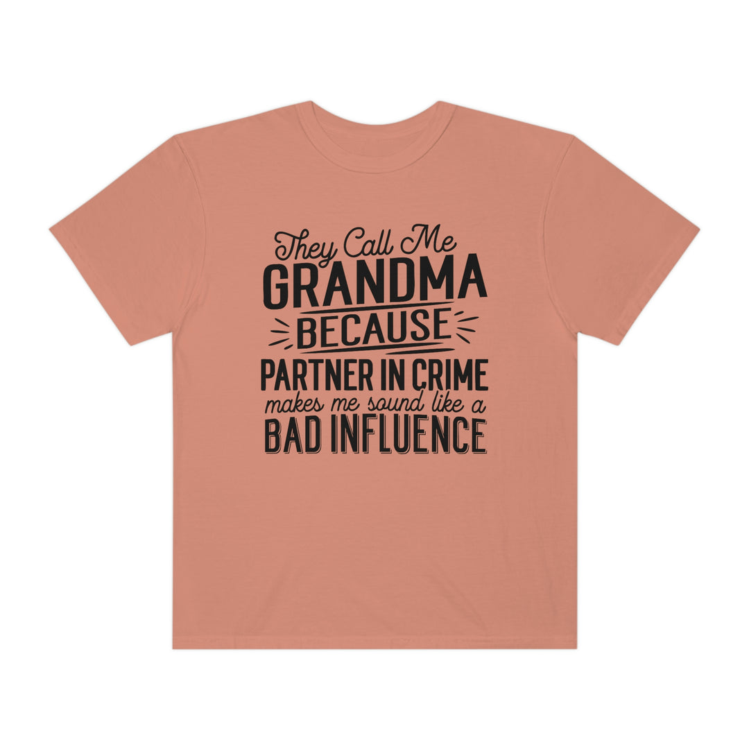 A ring-spun cotton tee, They Call Me Grandma Tee, with black text. Garment-dyed for coziness, featuring a relaxed fit and double-needle stitching for durability. No side-seams for a tubular shape.