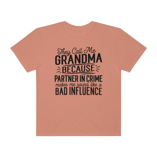 A ring-spun cotton tee, They Call Me Grandma Tee, with black text. Garment-dyed for coziness, featuring a relaxed fit and double-needle stitching for durability. No side-seams for a tubular shape.