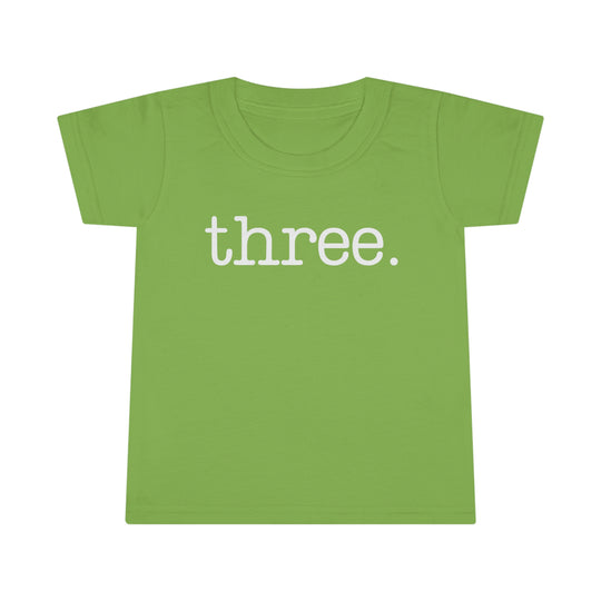 A durable Three Toddler Tee in green with white text. Classic fit, high stitch density, double-needle collar, sleeve, and bottom hems for comfort and longevity. Made of 100% Ringspun cotton.