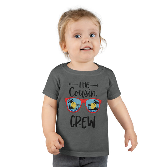 A Cousin Crew Toddler Tee by Worlds Worst Tees, featuring a child in a grey shirt with black letters. Classic fit, durable with double-needle collar, sleeve, and bottom hems. Made of 100% Ringspun cotton.