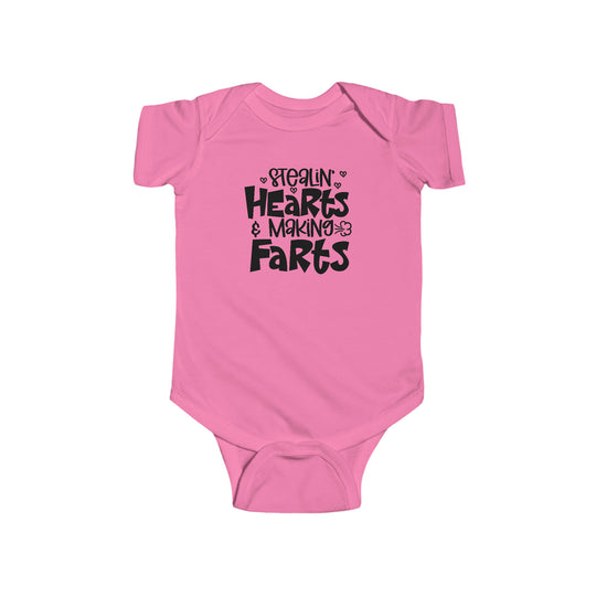 A pink baby bodysuit with black text, featuring the playful title Stealin Hearts and Making Farts Onesie. Made of 100% cotton, with ribbed knitting for durability and plastic snaps for easy changing access. From Worlds Worst Tees.