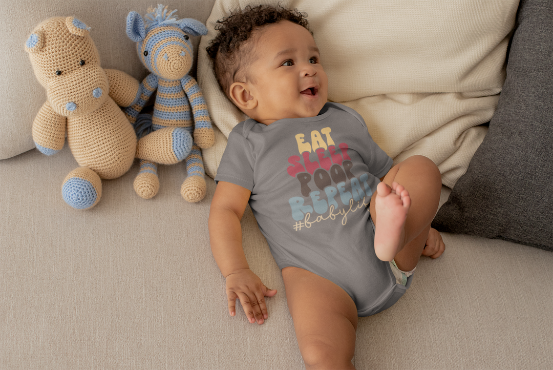 A baby lies on a couch surrounded by stuffed animals, wearing the Eat Sleep Poop Onesie from Worlds Worst Tees. This 100% cotton bodysuit features ribbed bindings and plastic snaps for easy changes.