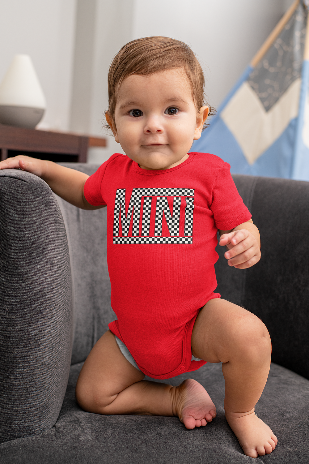 A Vans Mini Onesie for infants, featuring durable 100% cotton fabric with ribbed knit bindings and plastic snaps for easy changing. Combed ringspun cotton ensures softness and comfort. Sizes available: NB (0-3M), 6M, 12M, 18M, 24M.